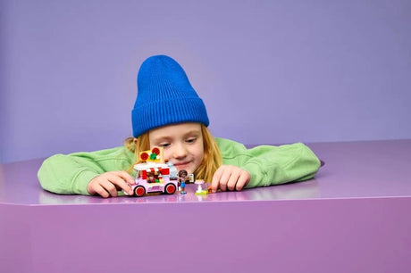 Child playing with LEGO Pizza Truck build on a purple table