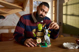 Adult adjusting the LEGO Shrek, Donkey & Puss in Boots 72423 model on a table, showing Shrek, Donkey and Puss in Boots.