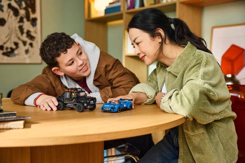 Child playing with the LEGO Speed Champions Jaguar Project 7 and Land Rover Defender 77264 models at a table