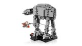 Side view of the completed LEGO Star Wars AT-AT walker on its black display stand, with the orange and white Rebel Snowspeeder and tow cable around the walker's legs.