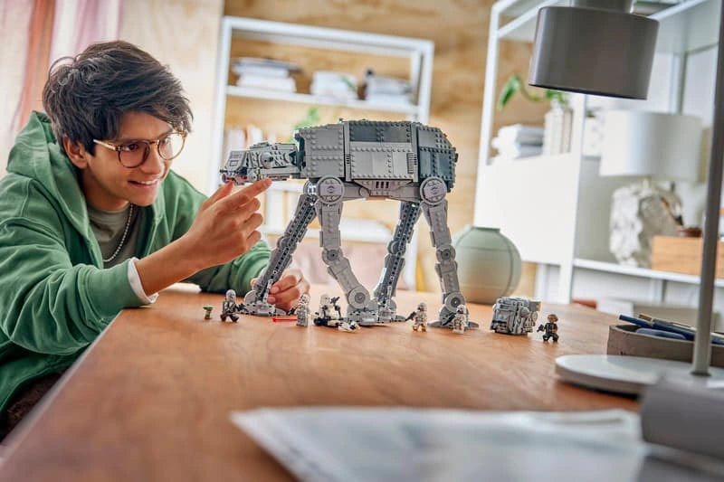 Child playing with the assembled LEGO Star Wars Imperial Remnant AT-AT walker, minifigures and escape pod on a table.