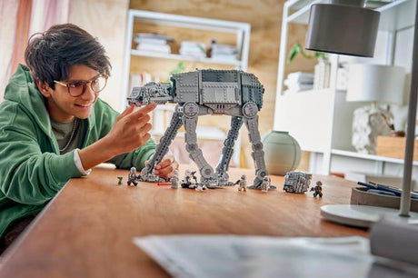 Child playing with the assembled LEGO Star Wars Imperial Remnant AT-AT walker, minifigures and escape pod on a table.