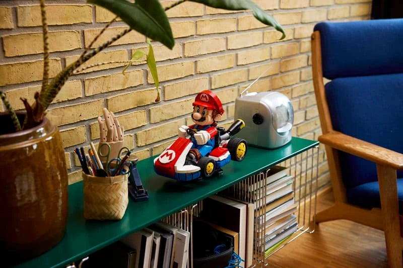 Completed LEGO Mario & Standard Kart model displayed on a green shelf beside books, stationery and a silver ornament