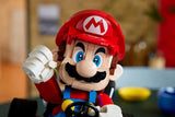 Close view of the LEGO Mario figure behind the steering wheel with one white gloved fist raised