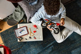 Child holding the LEGO Technic Ducati Desmo450 MX Factory Motorcycle 42238 model with loose parts and a tablet beside them