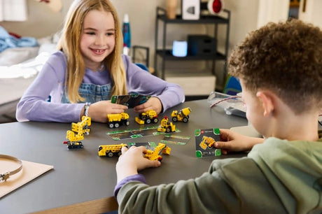Two children playing with LEGO Technic Mighty Machines 42233 construction vehicles and road cards