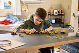 Child arranging a lineup of LEGO Technic Mighty Machines 42233 construction vehicles on a table 