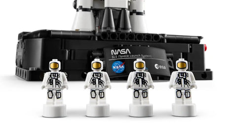 Four LEGO Technic NASA astronaut nanofigures lined up in front of the Artemis rocket display base