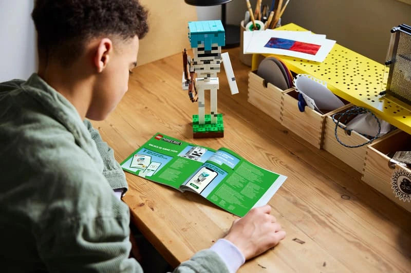 Child looking at LEGO Minecraft skeleton build and instruction booklet on a desk