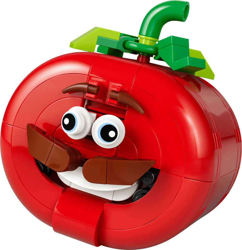 Close-up of LEGO red tomato head model with green stem, eyebrows, eyes, moustache and smiling mouth