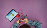 Child building a LEGO tomato head model at a table with tablet instructions