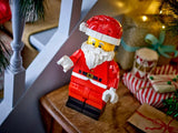 LEGO Santa figure beside a staircase with wrapped presents and Christmas greenery