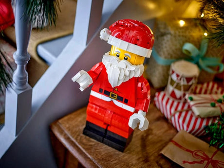 LEGO Santa figure beside a staircase with wrapped presents and Christmas greenery