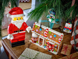 LEGO Santa figure beside a gingerbread house with two snowman ornaments hanging from the tree