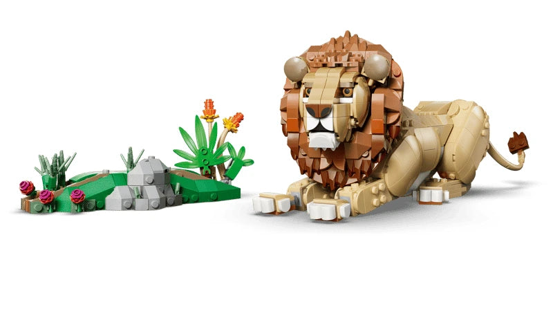 LEGO lion model resting beside a savanna habitat build with rocks and plants