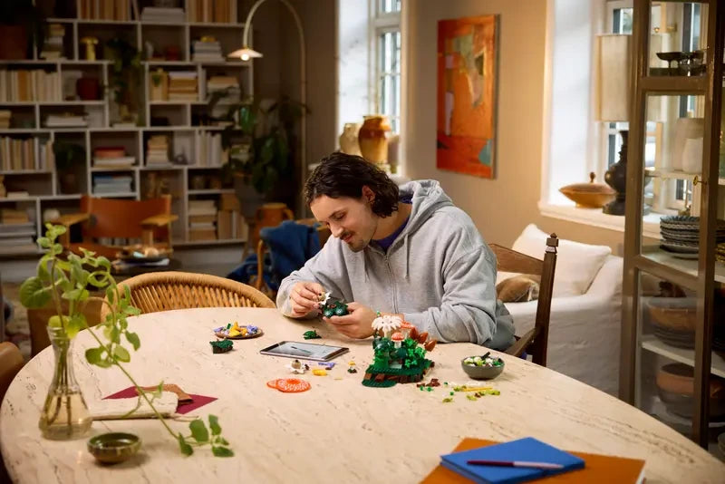 Person building LEGO Woodland Mushrooms at a table with pieces and instructions visible