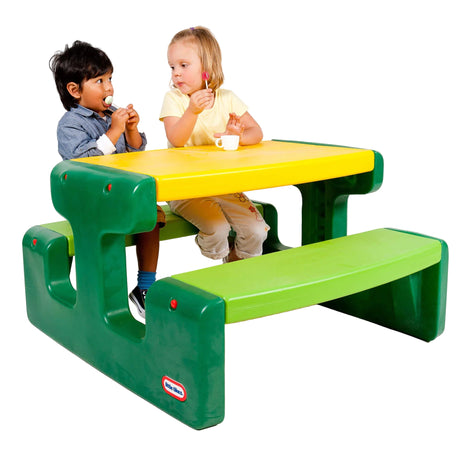 Two children eating lollipops at the green and yellow Little Tikes picnic table