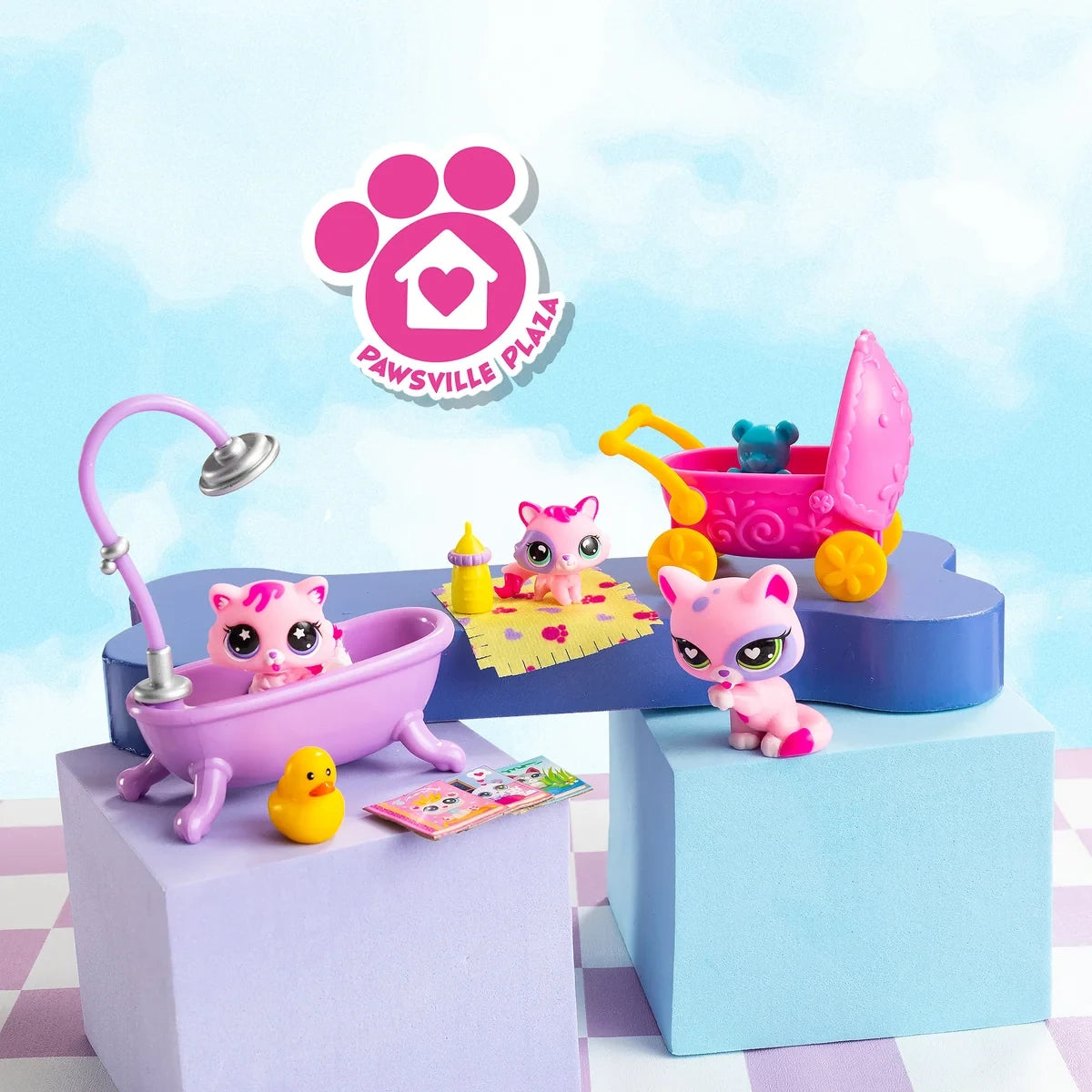 Three Littlest Pet Shop cat figures displayed with a purple bathtub, pink baby pram, rubber duck, baby bottle and miniature books on pastel blue and purple platforms.