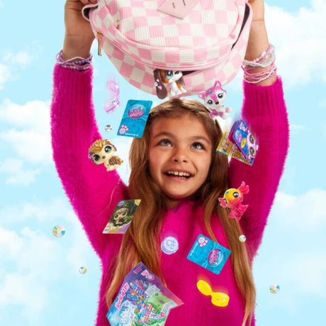 Smiling girl in a bright pink jumper lifting a pink checkered bag above her head, with Littlest Pet Shop animal figures and accessories around her.