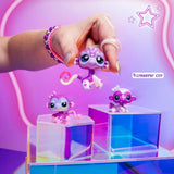 Purple Littlest Pet Shop monkey mother and baby figures displayed on colourful transparent blocks, with a hand holding the larger monkey figure above the others.