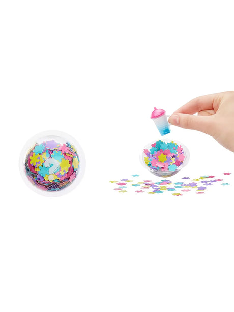 Surprise Big Surprise Party unboxing scene with confetti-filled ball opened and hand holding a small pink and blue bottle accessory