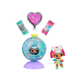 L.O.L. Surprise Bubbly Surprise Tot doll beside a transparent turquoise reveal capsule on a purple stand, with a pink heart shaped container and two packets of colourful decorative ingredients displayed above.