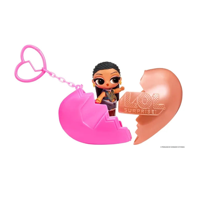 L.O.L. Surprise Music Festival Headliners Tots miniature doll with dark braided hair and a blue butterfly patterned outfit, standing inside an opened pink and rose gold heart capsule with a pink heart shaped keychain.