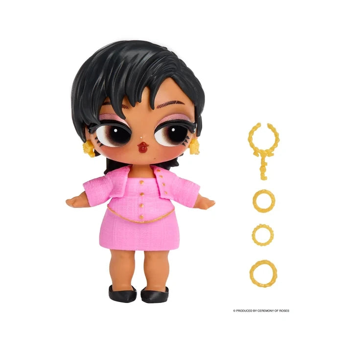 L.O.L. Surprise Music Festival Headliners Tots doll wearing a pink outfit and black shoes, with short swept black hair, star shaped earrings and separate gold jewellery accessories displayed alongside.