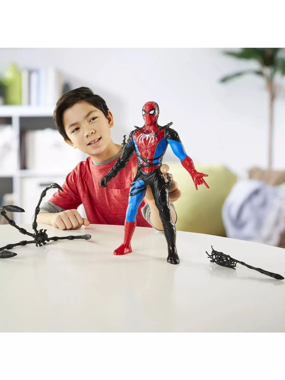 Child playing with the Hasbro Marvel Spider-Man Liquid Shifter Venom Versus action figure on a table, showing the figure's size relative to a school-age child with symbiote accessories laid out