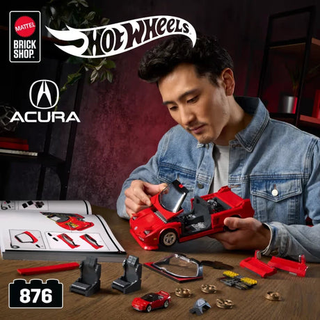 Person assembling a red Hot Wheels Acura NSX model beside instructions, tools, small parts and a 1:64 car