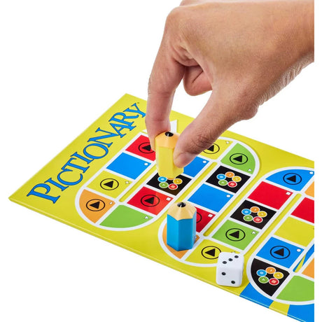Hand moving a yellow mover on the Pictionary gameboard with die and card box nearby
