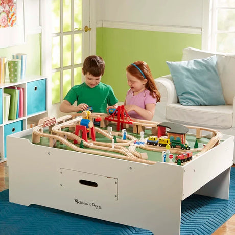 Two children moving toy trains on the Melissa & Doug Deluxe Wooden Multi-Activity Play Table