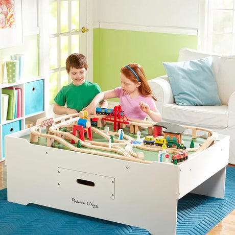 Two children playing at the Melissa & Doug Deluxe Wooden Multi-Activity Play Table with a wooden train layout