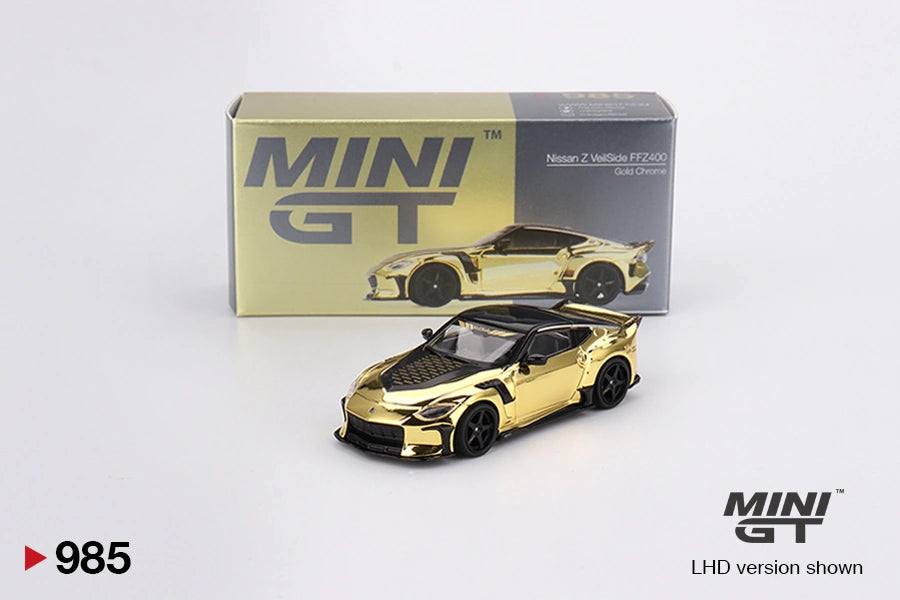 Mini GT Nissan Z VeilSide FFZ400 Gold Chrome diecast car shown from the front with black bonnet, black wheels and illustrated Mini GT collector box behind it