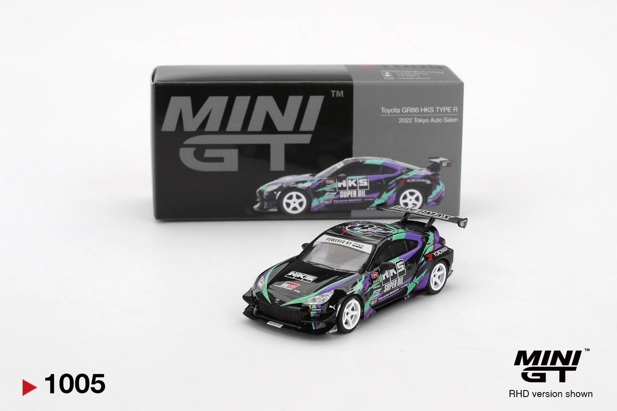 Mini GT Toyota GR86 HKS Type R 2022 Tokyo Auto Salon diecast car with black, green and purple racing graphics, white wheels and large rear wing, displayed in front of its Mini GT collector box