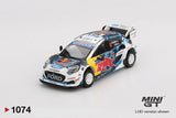 Mini GT Ford Puma Rally1 No.16 front three quarter view showing Ford grille, Red Bull bonnet graphics, white rally wheels, roof scoop and large rear wing
