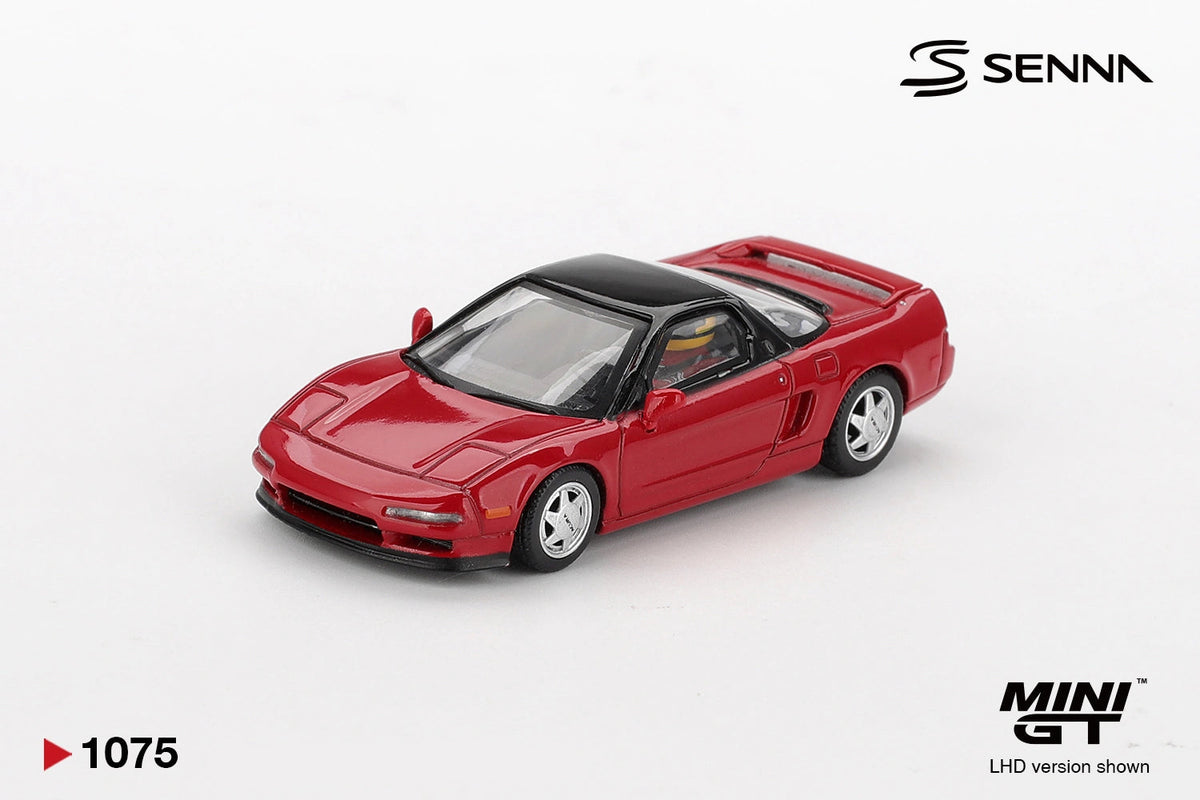 Mini GT Honda NS-X Ayrton Senna model photographed from the front three quarter angle, showing the red bodywork, black roof and seated driver wearing a yellow and green helmet
