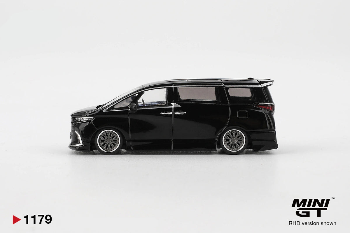 Side profile of Mini GT Toyota Alphard 40 KUHL Black RHD showing lowered black bodywork, silver multi spoke wheels, sliding door handles, tinted windows and rear roof spoiler.