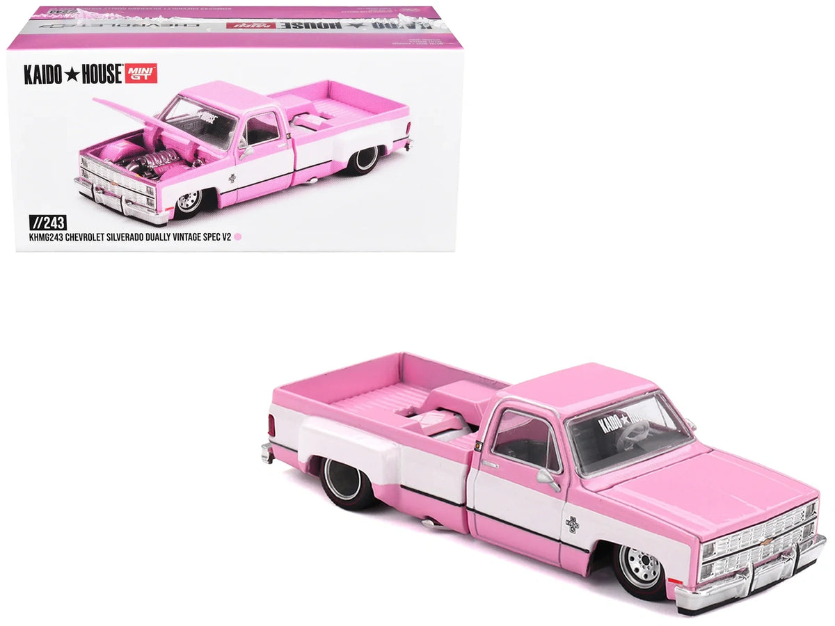 Mini GT Chevrolet Silverado Dually Vintage Spec V2 pink and white diecast pickup displayed beside its Kaido House collector box with KHMG243 model number