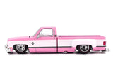 Side profile of Mini GT Chevrolet Silverado Dually Vintage Spec V2 showing pink and white bodywork, lowered stance, silver wheels and extended rear wheel arches