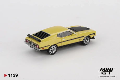 Rear three quarter view of Mini GT Ford Mustang Mach 1 Grabber Yellow LHD showing the black rear window louvres, rear spoiler, chrome bumper, dual exhaust pipes and black side stripes