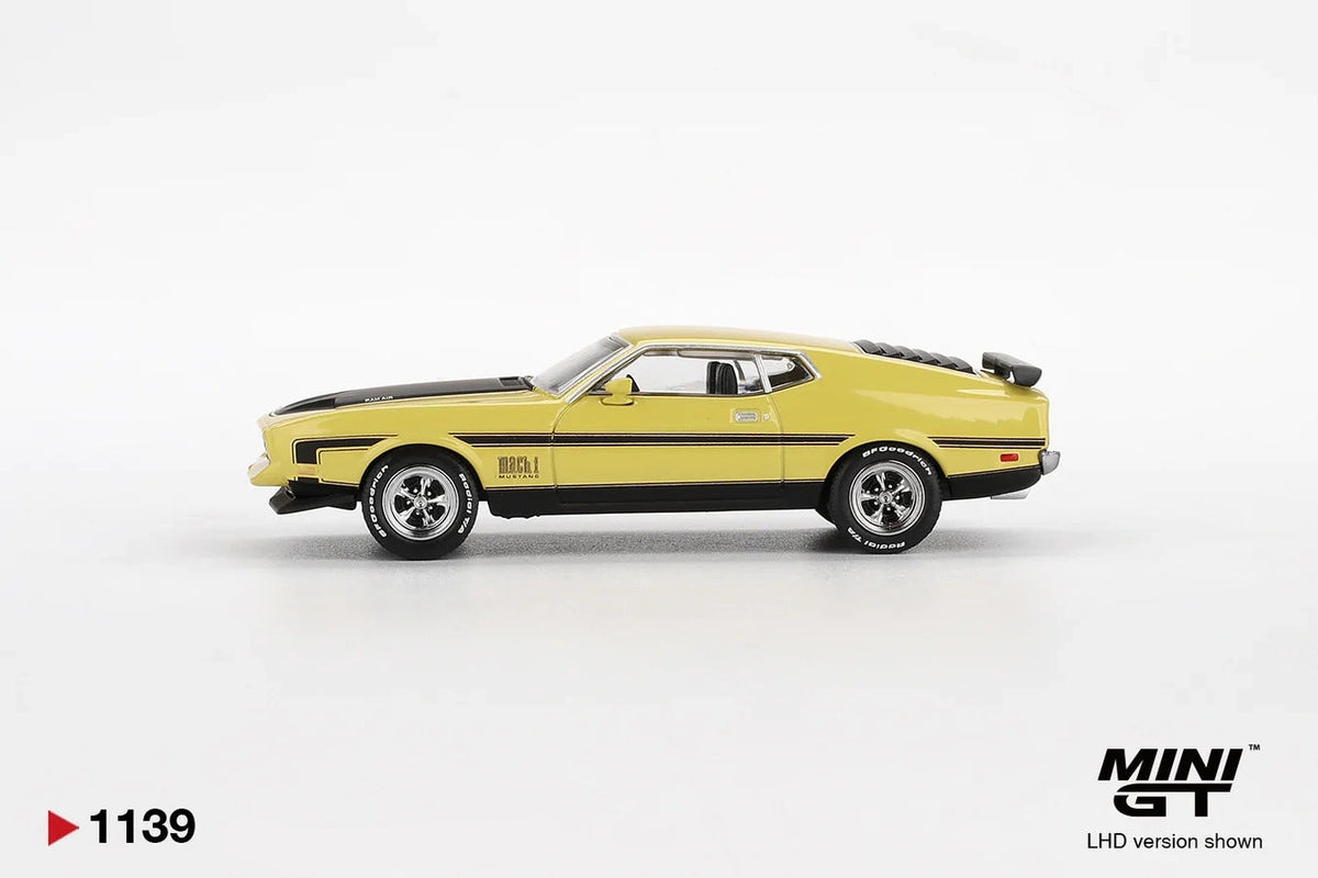 Side profile of Mini GT Ford Mustang Mach 1 Grabber Yellow LHD showing the yellow fastback body, black side stripes, Mach 1 badging, chrome wheels and raised bonnet scoop
