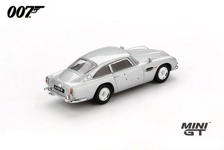 Mini GT James Bond Skyfall Aston Martin DB5 Battle Damaged RHD rear three-quarter view showing bullet marks across the body and rear quarter
