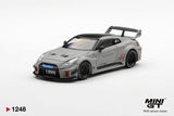 Front three-quarter view of Mini GT Nissan LB-Silhouette WORKS GT 35GT-RR Matt Grey RHD showing the blue grille accent, black bonnet vents, extended front splitter, Liberty Walk graphics and black racing wheels.