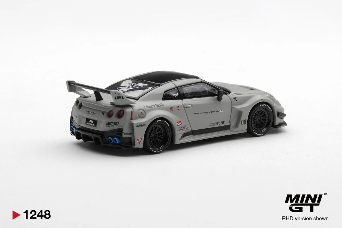 Rear three-quarter view of Mini GT Nissan LB-Silhouette WORKS GT 35GT-RR Matt Grey RHD showing four round taillights, blue exhaust tips, black rear diffuser, Liberty Walk branding and large racing wing.