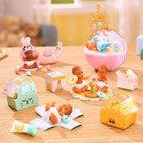 Miniverse Real Baby Nurture miniature baby care scenes arranged on a wooden table, featuring babies in a bunny towel, a pink bassinet, a changing mat and playing with stacking rings, surrounded by tiny baskets and accessories.