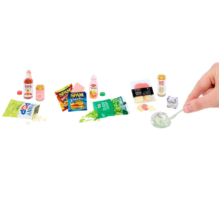 Miniverse Real Brands Series 2 miniature groceries including SPAM packets, Tapatío hot sauce, Boursin cheese, snack packets and small bottles, with a hand holding a tiny spoon of cheese.
