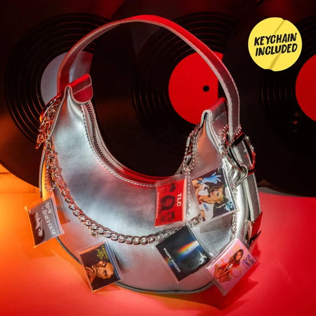 Silver handbag decorated with miniature album cover keychains featuring artists including TLC, Britney Spears and Imagine Dragons, against a background of black vinyl records.
