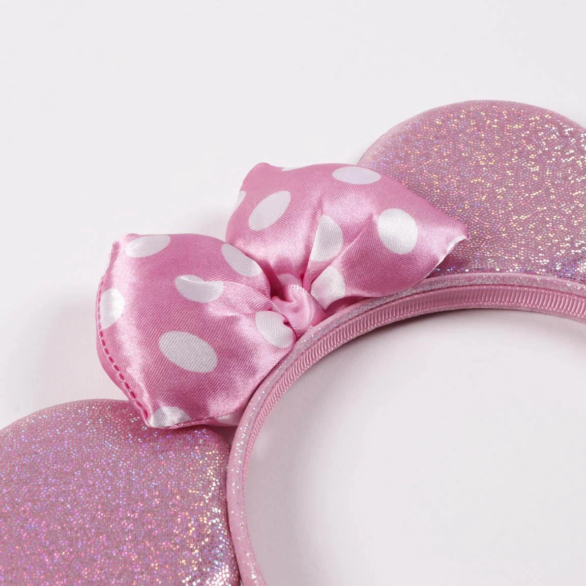 Close view of Minnie Mouse pink glitter ear headband showing the white polka dot satin bow and sparkly ears