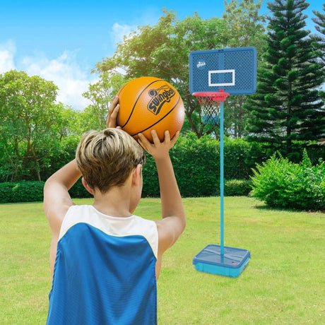 Mookie All Surface Basketball hoop on grass with a child holding an orange basketball